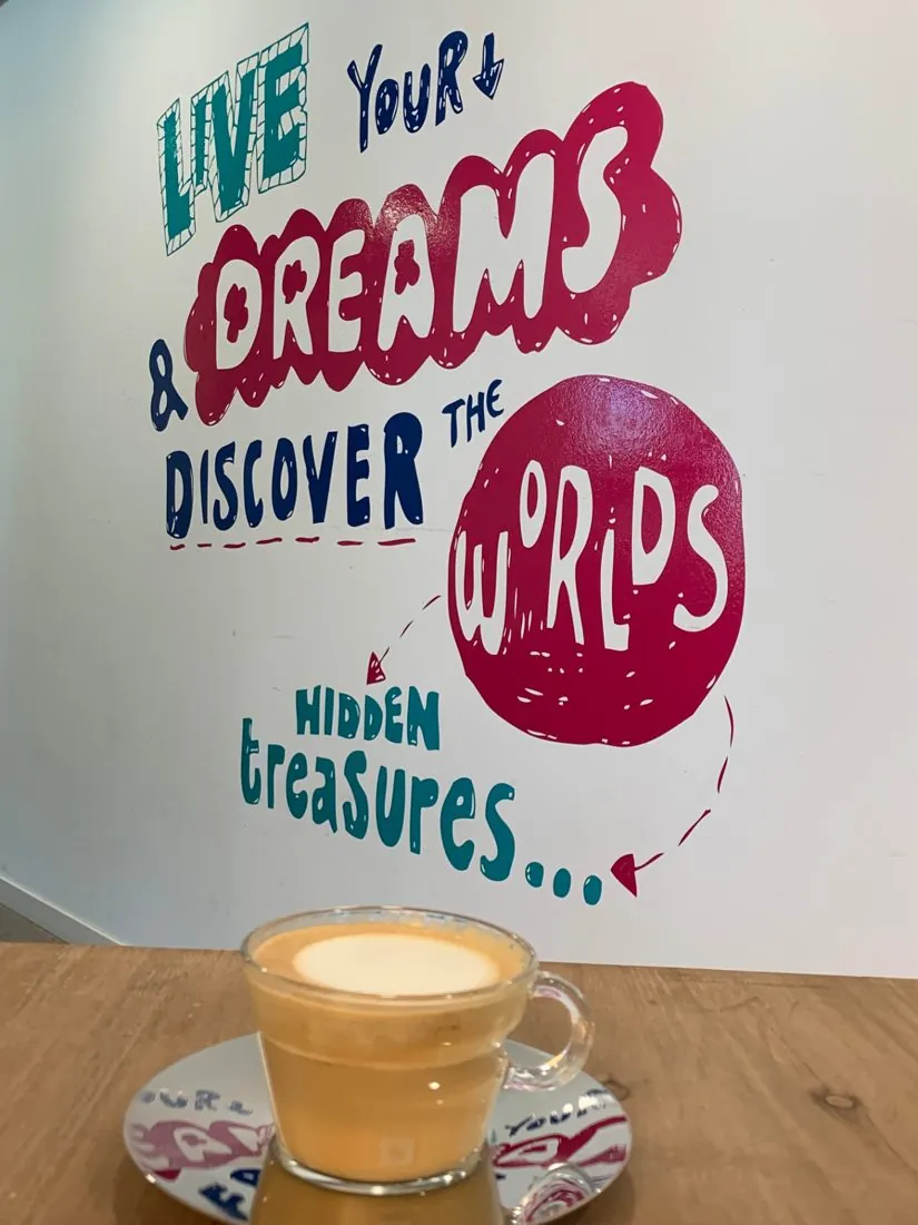 Coffee cup in front of a hand-lettered office wall mural