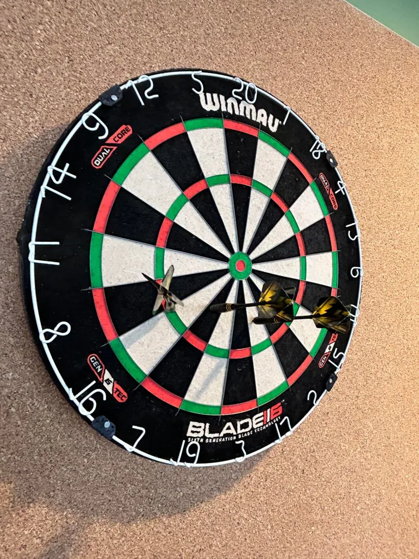 Dartboard on an office wall with darts in it