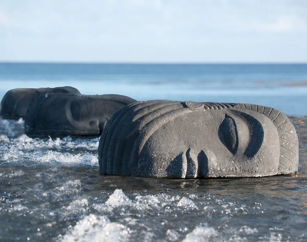 Carved stone faces resting in shallow sea water